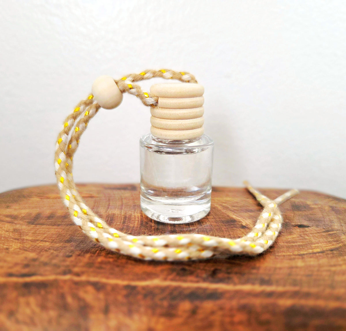 Small vial of Verdant Home & Co hanging diffuser on a wooden surface with a white background.