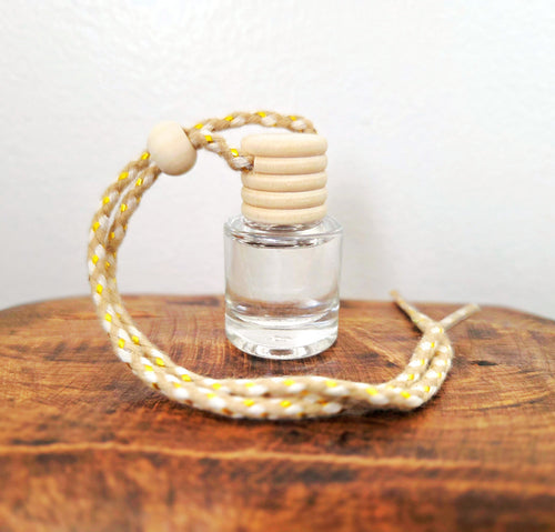 Small vial of Verdant Home & Co hanging diffuser on a wooden surface with a white background.