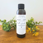 Bottle of Verdant Home & Co concentrate on a wooden surface with greenery and flowers.