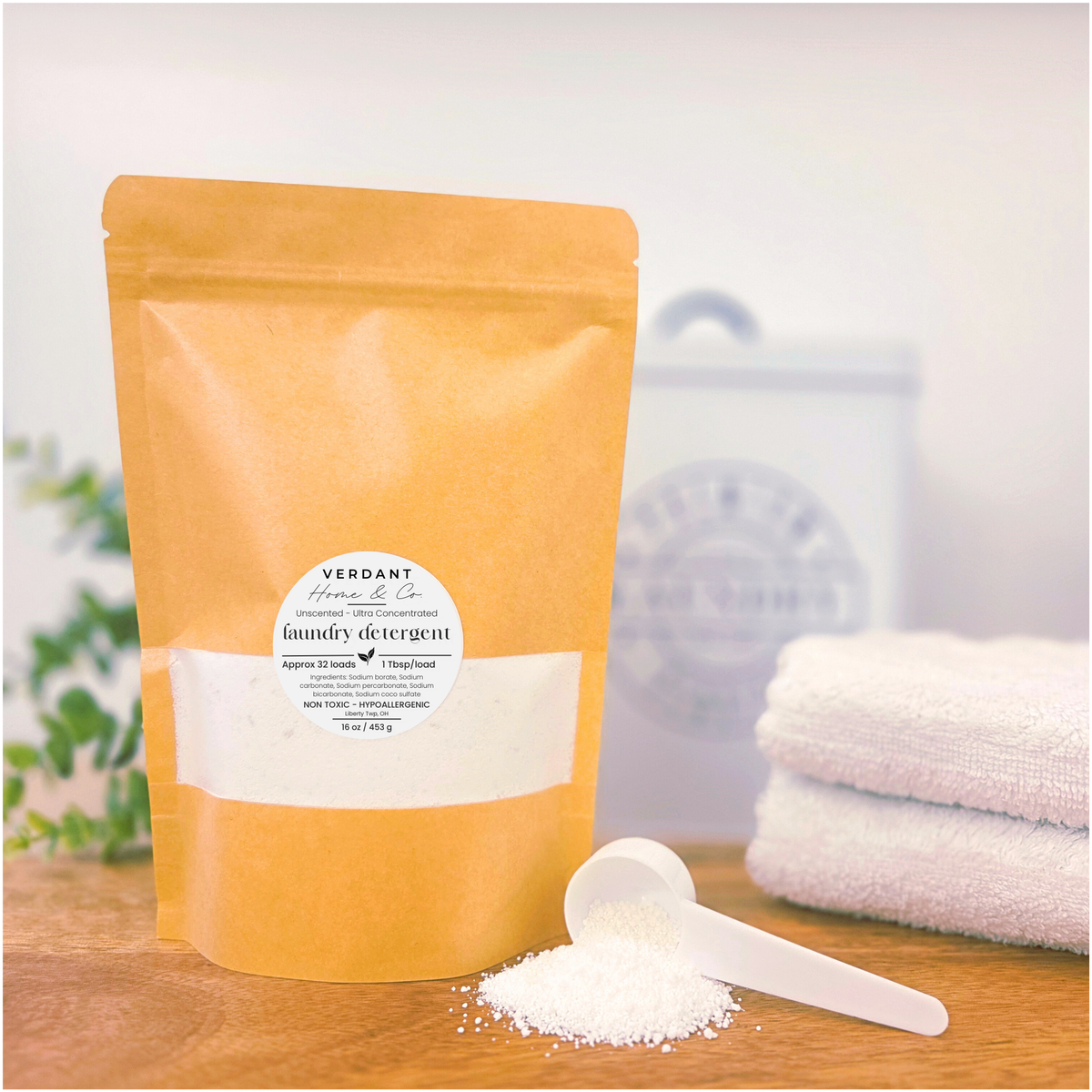 Yellow package of Verdant Home & Co laundry detergent with a scoop of powder on a wooden surface.