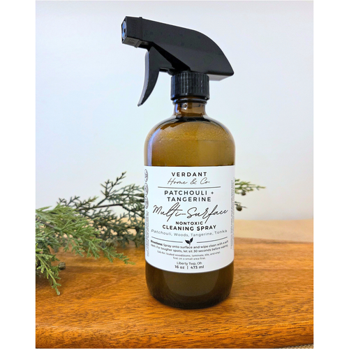Bottle of Verdant Home & Co. Patchouli + Tangerine cleaning spray on a wooden surface with a light background