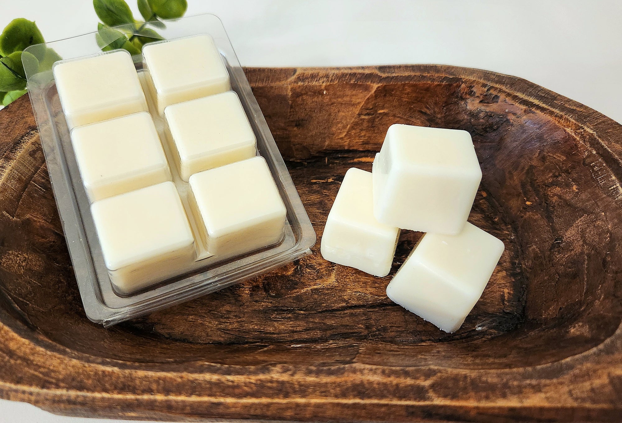 White wax melts in a clear mold on a wooden surface, no label