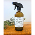 Bottle of Verdant Home & Co. multi-surface cleaning spray on a wooden surface with greenery.