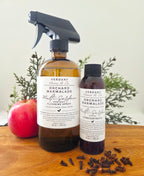 Two bottles of Verdant Home & Co Orchard Marmalade Multi-Surface Cleaning Spray on a wooden surface with plants in the background.